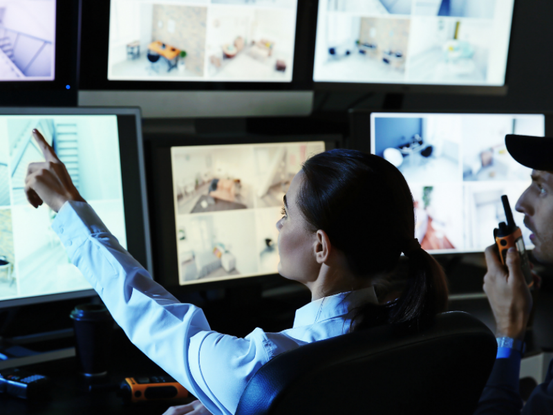 commercial alarm response with 2 guards looking at cctv and surveillance footage on screens